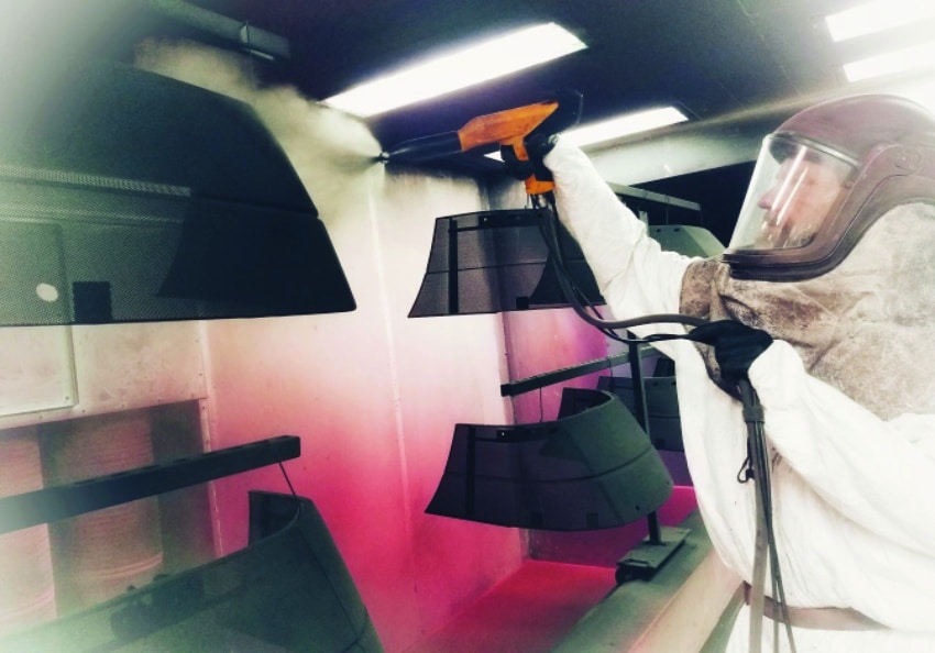Technician applying powder coat in the cross-draft booth